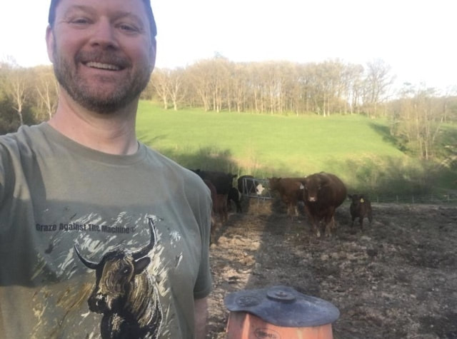 Brian wearing a Pineywoods Cattle Art t-shirt in front of his herd of Angus and Hereford cattle