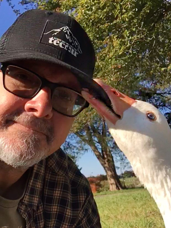Selfie with our Cotton Patch Goose, Cotton. He's chewing on my cap.