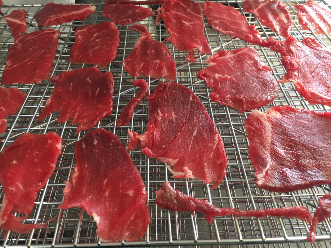 A stainless steel jerky rack with many thin slices of pineywoods beef