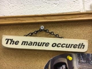 A sign on a bulletin board reading The Manure Occureth