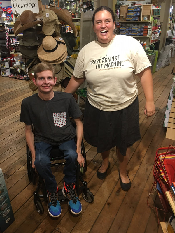 A woamn wearing a Graze Againt The Machine t-shirt stands next to a young man in a wheelchair